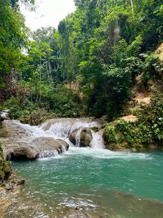 there is a small waterfall in the middle of some rocks and green trees around it