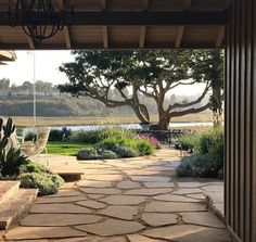 an outdoor patio with stone steps leading to a tree and water in the back ground