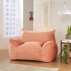 a pink bean bag chair sitting on top of a hard wood floor next to a white brick wall