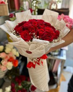 a bouquet of red roses is being held by someone