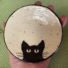 a hand holding a black and white cat bowl