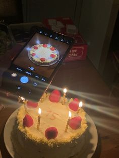 a birthday cake with candles on it and a cell phone showing the candle lit image