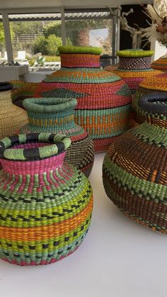 several woven baskets sitting on top of a white table next to each other, all different colors