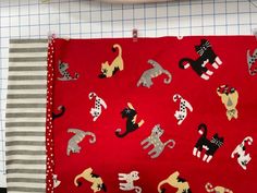 a piece of red fabric with black and white cats on it next to a sewing machine