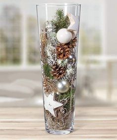 a glass filled with christmas decorations on top of a wooden table