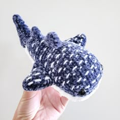 a hand holding a knitted toy that looks like a shark