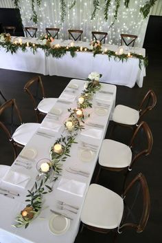 a long table is set with white plates and place settings