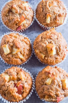 several muffins are sitting in the middle of a tray with apples on top