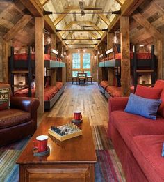 a living room filled with lots of red couches next to a wooden floor covered in bunk beds