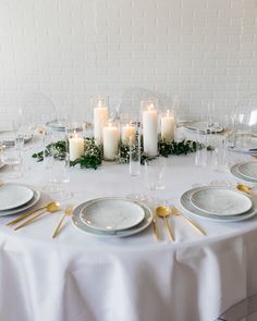 a white table topped with plates and candles