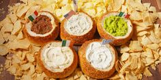 four sandwiches with chips and guacamole are arranged in a circle on a wooden table