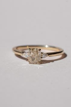 a yellow gold engagement ring with two diamonds on the band and an oval cut diamond in the center