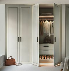 an open closet with shoes and handbags on the floor, next to a bed