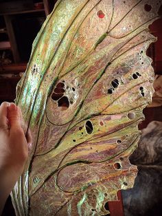 a person holding a large leaf with holes in it's center and other parts visible