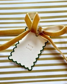 a gift wrapped in yellow ribbon with a white tag that says with love on it