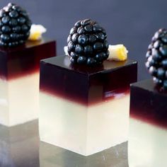 three desserts with blackberries and cream on them are arranged in cubes to look like they're ready to eat