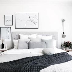 a bed with white sheets and pillows in a bedroom next to pictures on the wall