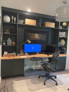 a desk with a computer on it in front of a bookshelf and shelves