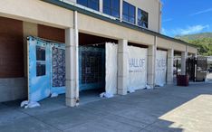 the front of a building with several doors covered in white tarp and some windows