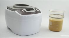 a blender next to a measuring cup with liquid in it on a white surface