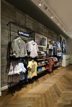 a clothing store with clothes on display and wooden floors in front of the wall,