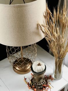 a table with a lamp and some dried plants on it