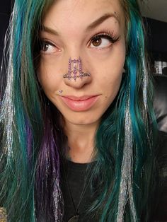 a woman with green and purple hair has her nose piercings in the shape of an m