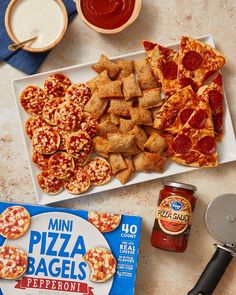 mini pizza bagels and pepperoni are on a plate next to some sauces