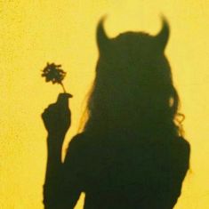 the shadow of a woman holding a flower in her hand and an animal head on it