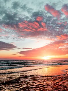 the sun is setting over the ocean with clouds in the sky and waves on the beach