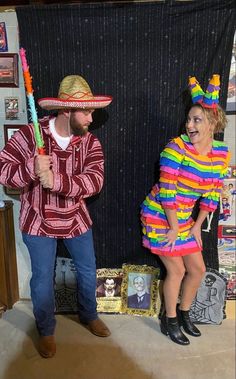 a man and woman dressed up as clowns in front of a blackboard with pictures on it