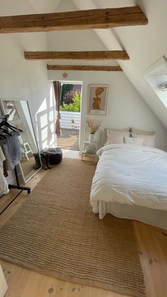 an attic bedroom with white bedding and natural wood flooring is pictured in this image