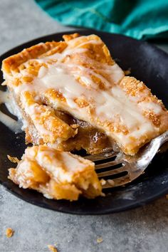 a piece of pie on a black plate with a fork