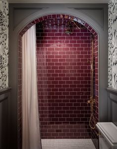 a bathroom with a red brick wall and white shower curtain