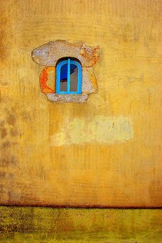 an old yellow wall with a blue window