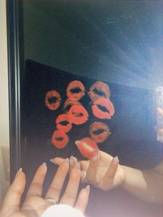 a woman's hands with manicured nails and red lipstick prints on the mirror