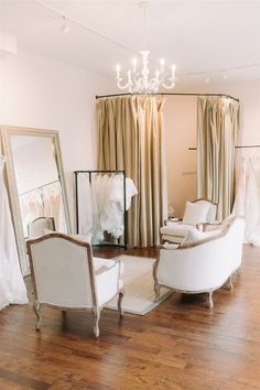 a living room filled with furniture and a chandelier hanging from the ceiling next to a mirror