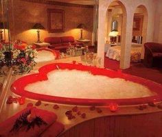 a large bath tub in the middle of a living room with flowers on the table