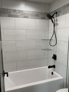 a white bath tub sitting inside of a bathroom next to a toilet and shower head