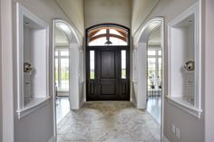 an entry way leading into a house with double doors and arched windows on both sides