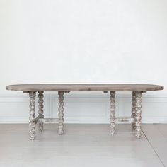 a wooden table sitting in the middle of a room next to a white wall and floor