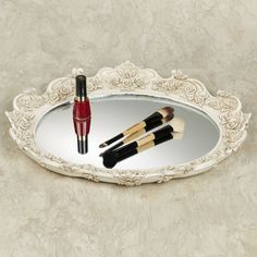 three makeup brushes sitting on top of a mirror next to a red bottle and brush