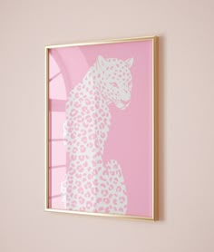 a pink and white leopard print hangs on the wall next to a framed photograph in a gold frame