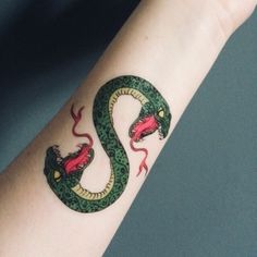 a hand with a green and red snake tattoo on it