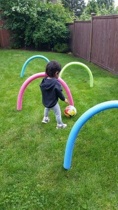 a toddler playing with an inflatable ball on the grass next to some blue and pink circles