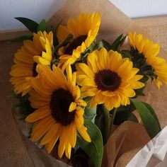 a bouquet of sunflowers in a brown paper bag