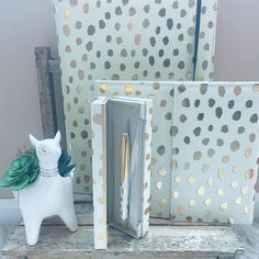 three decorative items sitting on top of a wooden table next to a white and gold polka dot wallpaper