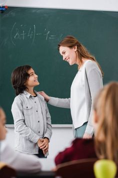 two women standing next to each other in front of a blackboard