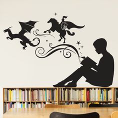 a man sitting on top of a wooden table next to a book shelf filled with books