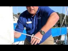 a man holding onto the end of a sailboat while wearing a blue shirt and khaki pants